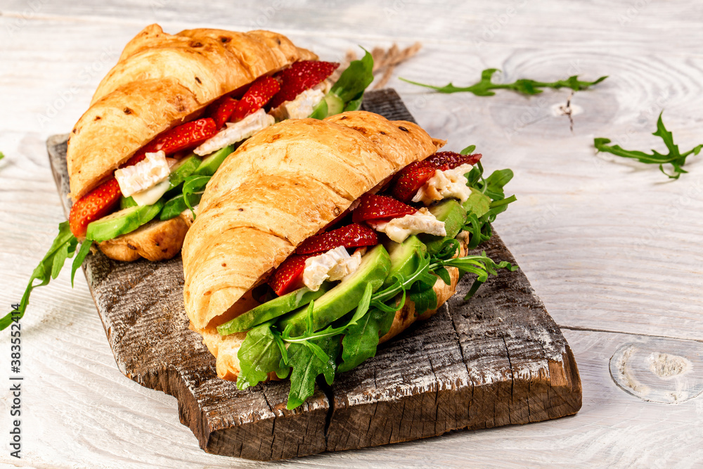 Breakfast, business lunch, sandwiches Croissant with strawberries and soft cheese with mold brie camembert on wooden background. banner menu recipe top view Breakfast, business lunch, sandwiches Croissant with strawberries and soft cheese with mold brie camembert on wooden background. banner menu recipe top view