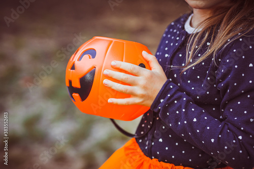Halloween kids. Little girl with jack o' lantern in witch hat with pumpkin candy bucket. Toddler kid in witch costume playing in autumn park. A Child in a carnival costume outdoors 