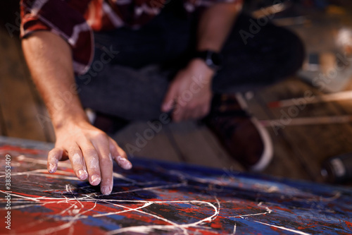 Artist works on abstract oil painting draws with his hands on the large canvas in creative modern studio. Abstract modern art.