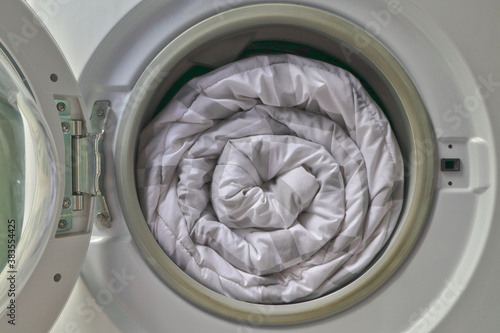 Billede på lærred Duvet rolls inside washing machine , Cleaning white blanket.