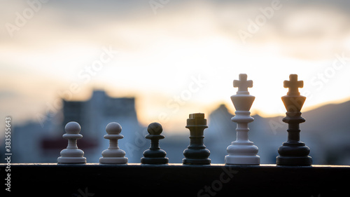 Black and white chess on the table with blurred background and orange light.