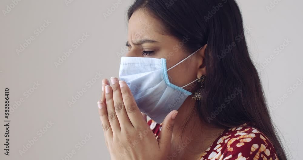Young Indian woman wearing a medical surgical mask in covid pandemic times of new normal following rules and regulations - ill flu cough unwell adjusting mask worried concerned symptoms aware spread Young Indian woman wearing a medical surgical mask in covid pandemic times of new normal following rules and regulations - ill flu cough unwell adjusting mask worried concerned symptoms aware spread