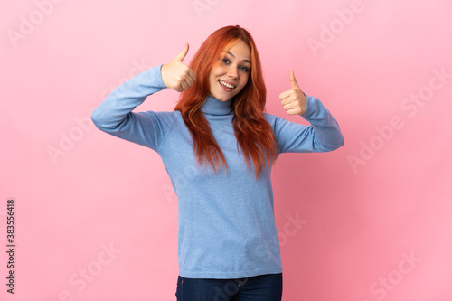 Teenager Russian girl isolated on pink background giving a thumbs up gesture