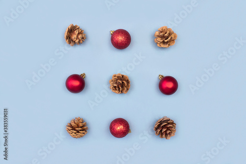 Square made of red christmas decorations and fir cones creative flat lay on blue background top view with copy space. Christmas pattern composition. Happy new year, xmas celebration concept.