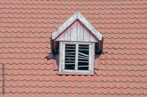 Brown tiled roof of a detached house. Ventilation window.