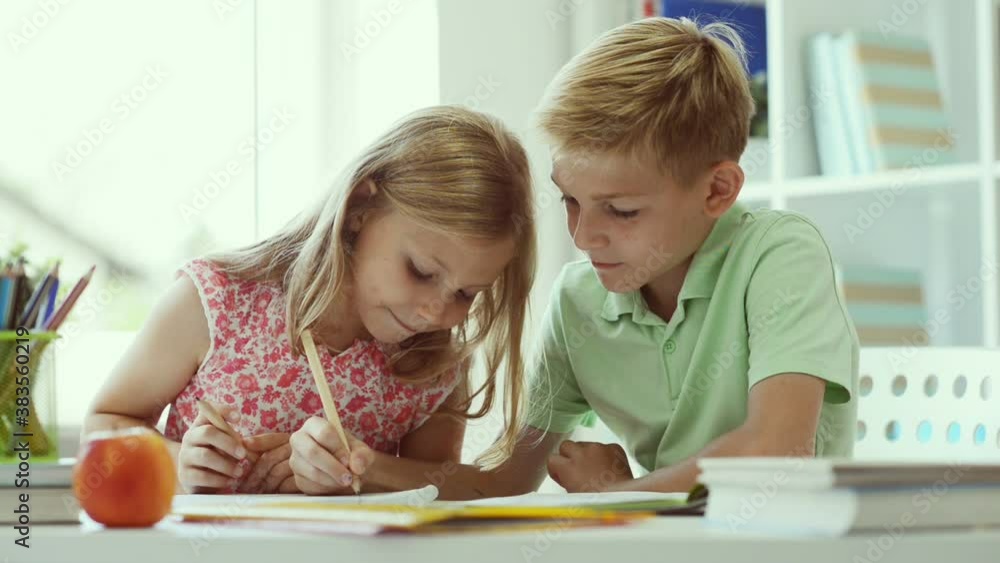 Two cute schoolchildren boy and girl doing homework at home Two cute schoolchildren boy and girl doing homework at home