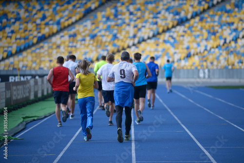 Group of people running on tracks of the stadium in the evening light