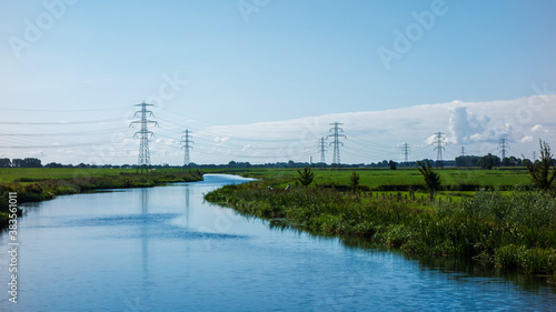 Fotografie Landscape with river and meadows and power pylons