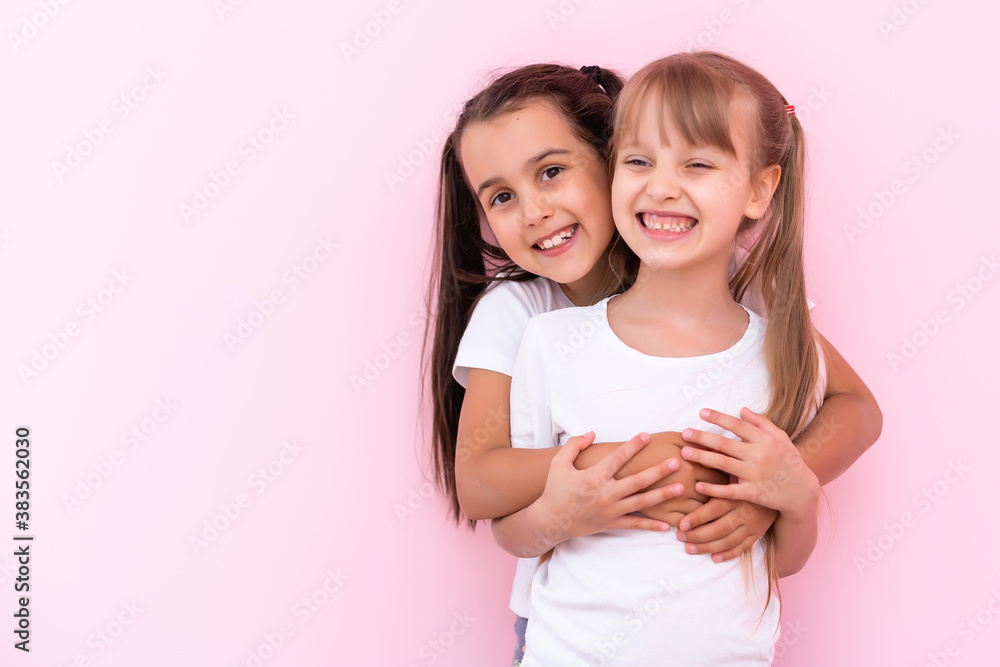 Two little girls hugging each other. Isolated on on a pink background Two little girls hugging each other. Isolated on on a pink background