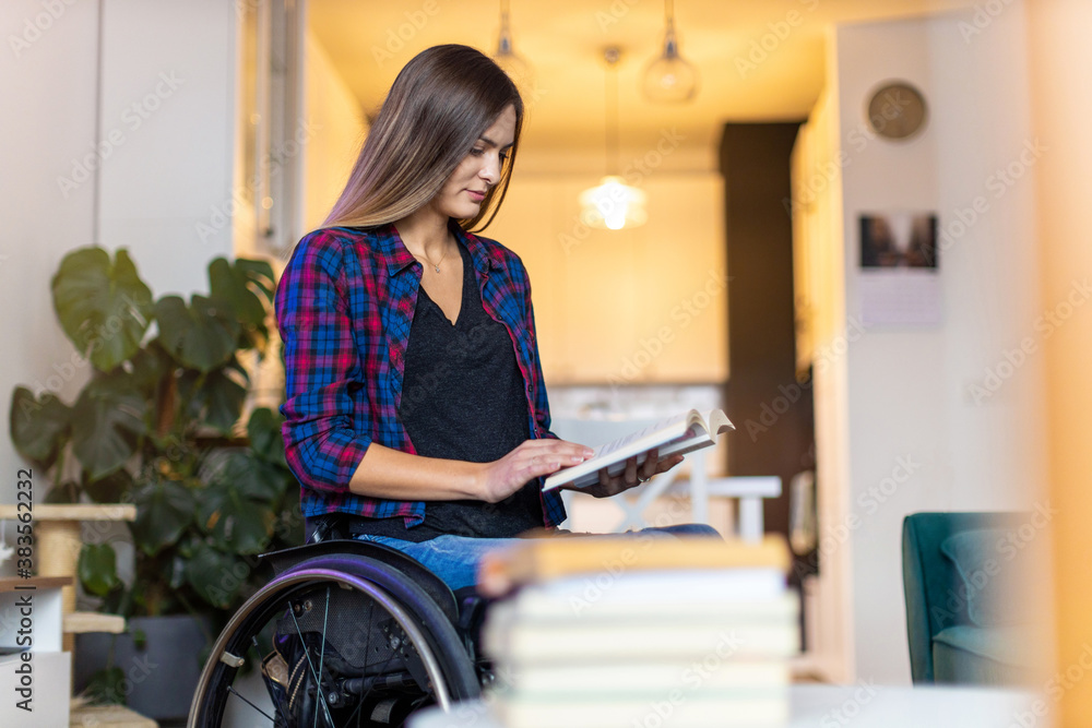 Woman in wheelchair reading book at home
Woman in wheelchair reading book at home