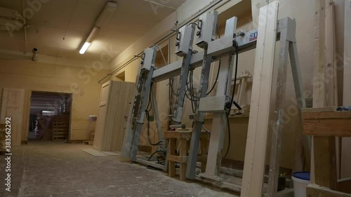 Large metal machine tool near stack of future wooden inner doors in empty woodworking plant workshop premises photo