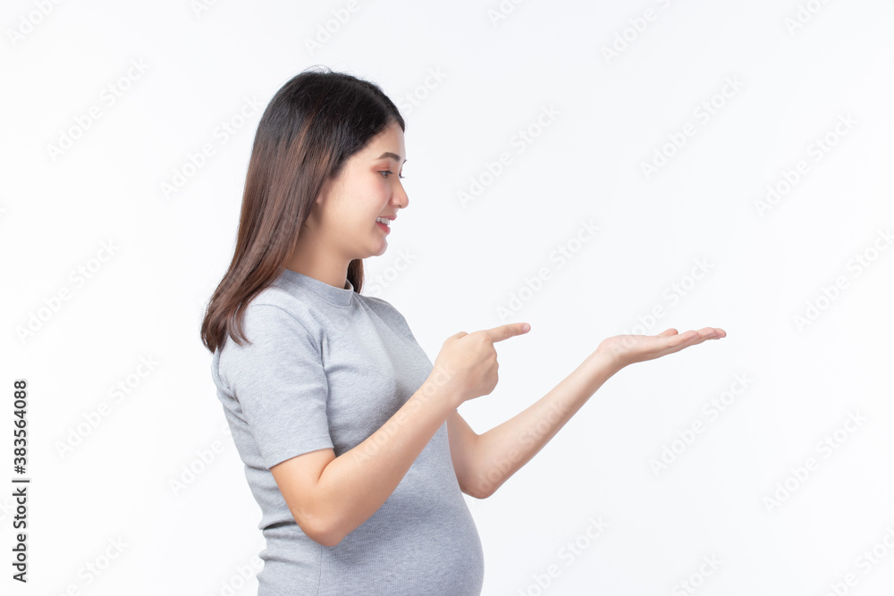 Young beautiful pregnant woman stand and touching belly showing empty copy space on the open hand palm for text isolated on white background. Pregnancy, motherhood, people and expectation concept. Young beautiful pregnant woman stand and touching belly showing empty copy space on the open hand palm for text isolated on white background. Pregnancy, motherhood, people and expectation concept.