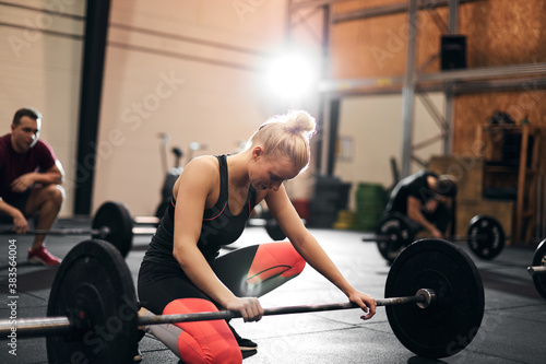 Fit young woman looking tired after a weightlifting session
