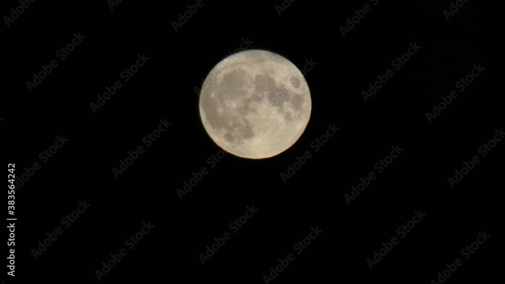 Full harvest moon lunar crater surface closeup passing across dark sky Full harvest moon lunar crater surface closeup passing across dark sky