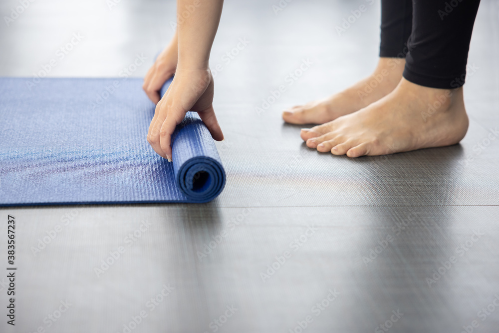 Close-up on Woman Folding Blue Yoga Mat on the Ground