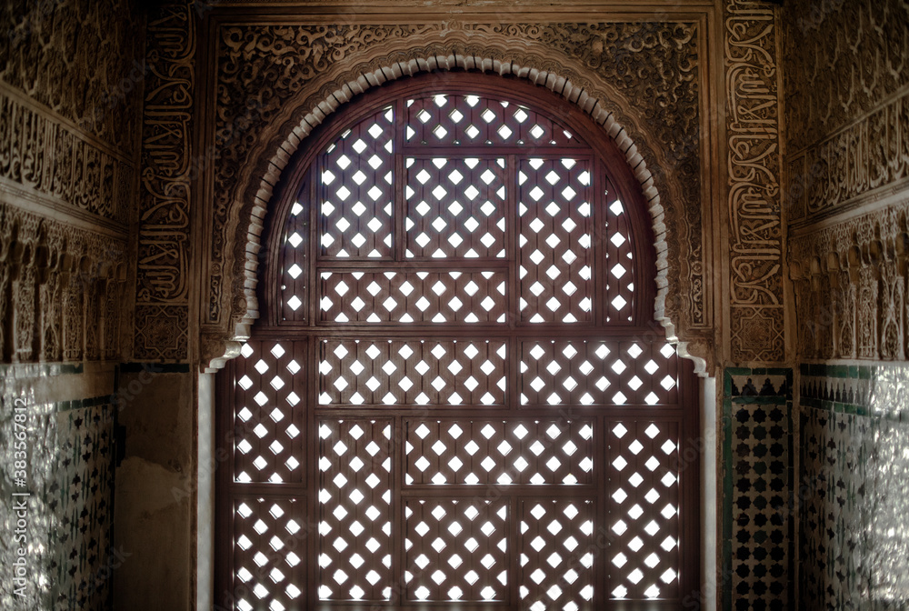 Beautiful architecture with an arch wooden door in the Moorish style at Nasrid Palace, Alhambra.