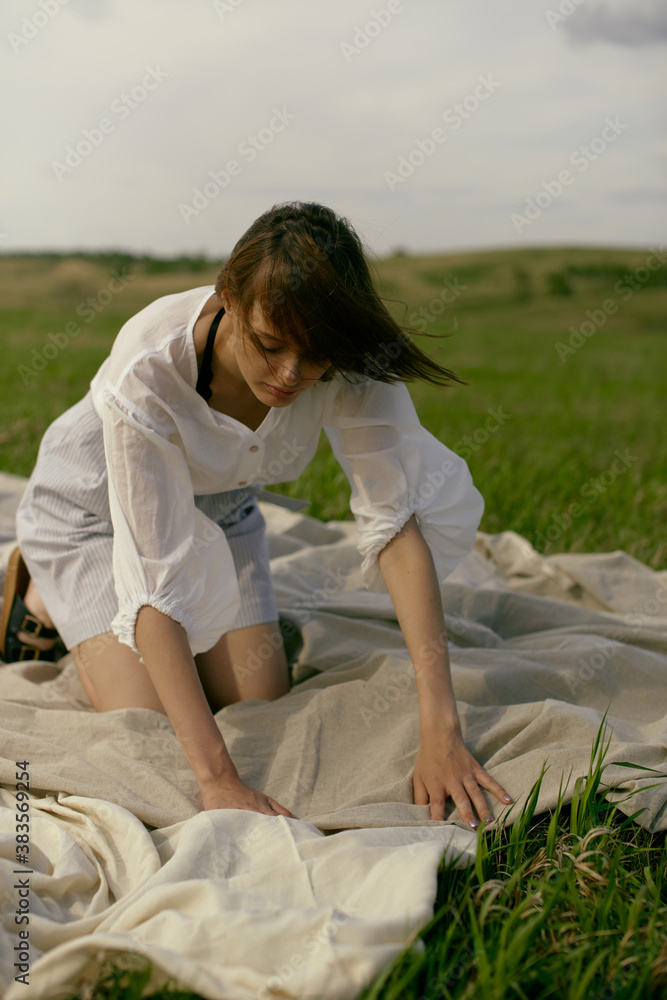 Nice picnic on the grass. Young beautiful woman in the middle of green field. Summer landscape, good weather. Windy day with sun and clouds. Cotton white suit eco style. Nice picnic on the grass. Young beautiful woman in the middle of green field. Summer landscape, good weather. Windy day with sun and clouds. Cotton white suit eco style.