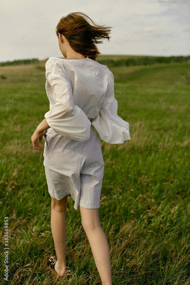 Nice picnic on the grass. Young beautiful woman in the middle of green field. Summer landscape, good weather. Windy day with sun and clouds. Cotton white suit eco style. Nice picnic on the grass. Young beautiful woman in the middle of green field. Summer landscape, good weather. Windy day with sun and clouds. Cotton white suit eco style.