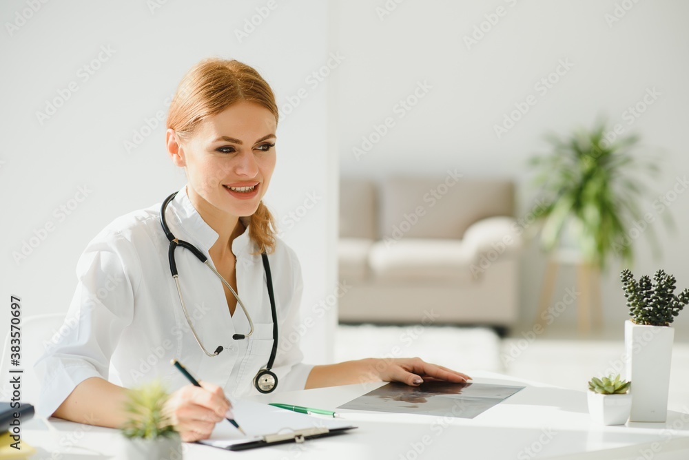 Female doctor working at office desk and smiling, office interior on background Female doctor working at office desk and smiling, office interior on background