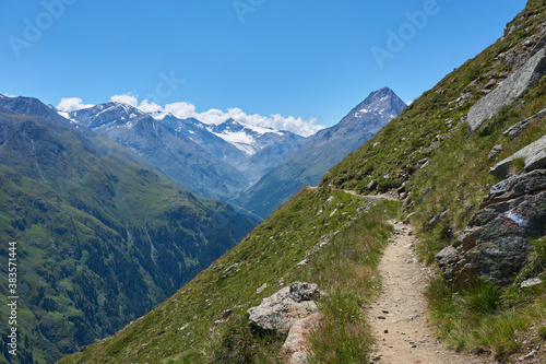 Bergweg am Rand eines grünen Berges beim Wandern in den Bergen Alpen Wanderweg