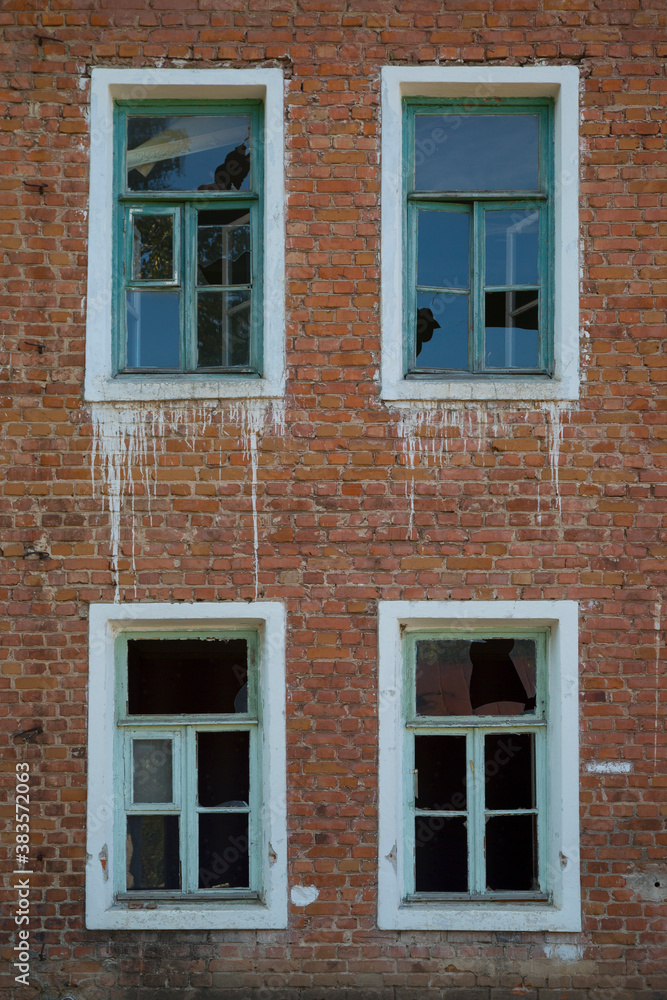 Vertical detail shot of vintage old brick wall with broken windows for background. Red and white contrast texture