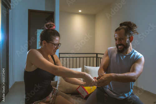 Pareja de novios casados comiendo palomitas viendo television pelicula en casa comodos