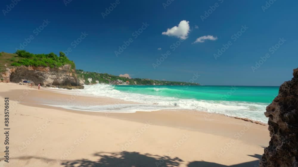 Sandy beach with rocky mountains and clear water of Indian ocean at sunny day. Bali, Indonesia Sandy beach with rocky mountains and clear water of Indian ocean at sunny day. Bali, Indonesia