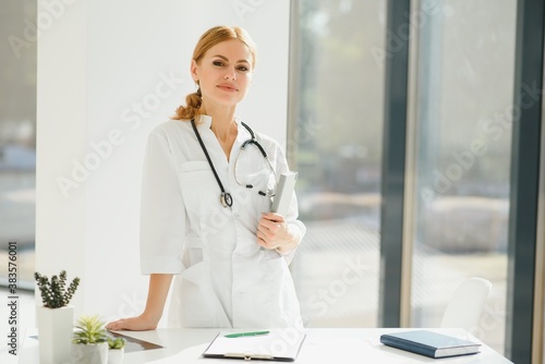 Portrait of attractive female doctor holding clipboard while standing in clinic © Serhii