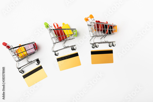 Top view of toy carts with gifts and credit cards on white background