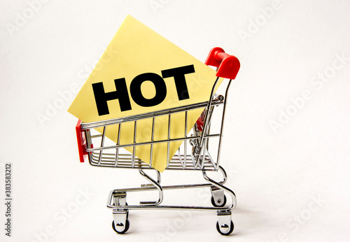 Shopping cart and text hot on yellow paper note list. Shopping list, business concept on white background.