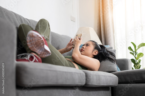 lazy sport woman lying with smartphone on sofa at home photo