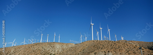 Group of aligned windmills against blue sky photo