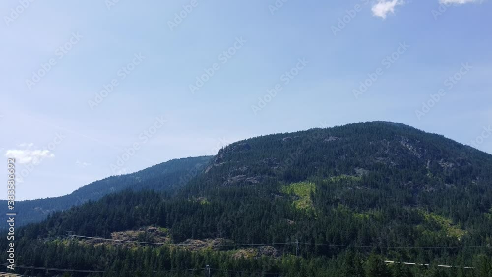Canadian mountain covered with the green trees on a sunny day with one cloud Canadian mountain covered with the green trees on a sunny day with one cloud