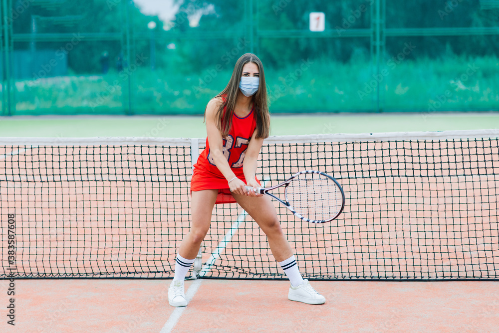 Portrait of tennis player girl holding racket outside with protective masks