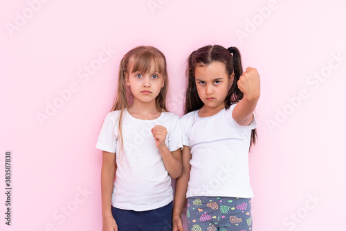 Pretty two child girls in white t-shirts with long hair, look at camera and down on tshirt