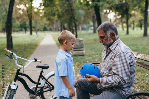 grandfather and grandson preparing for riding a bike in park