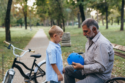 grandfather and grandson preparing for riding a bike in park © cherryandbees