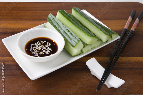 Soy Sauce With Cucumber Slices And Chopsticks On Table