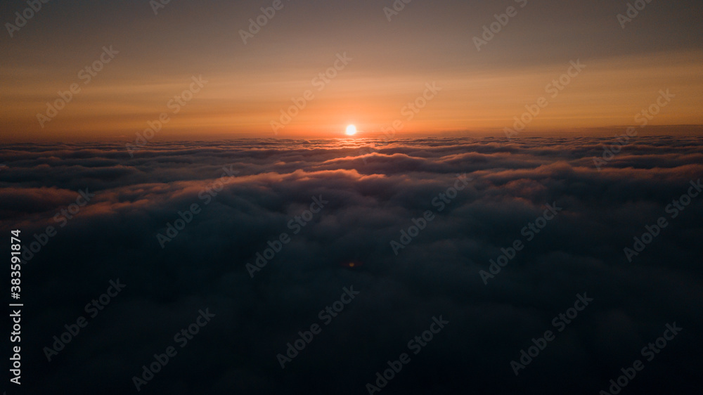 Aerial morning sunrise view over the clouds in the air with ocean fog and glowing clouds