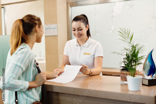 Happy receptionist talking to a customer at health spa. photo