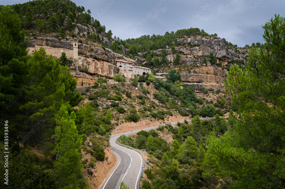 Winding road passing by the sanctuary of the Virgin of Balma built in the mountains on a cloudy day in Zorita del Maestrazgo, Castellon, Spain