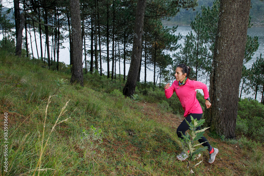 Atleta corriendo en el bosque subiendo una montaña que esta cerca de un lago Atleta corriendo en el bosque subiendo una montaña que esta cerca de un lago