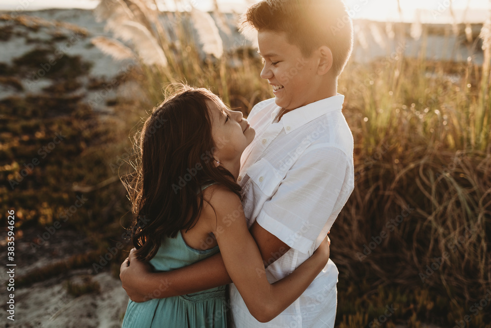 Smiling preteen boy wearing white shirt hugging his sister Smiling preteen boy wearing white shirt hugging his sister