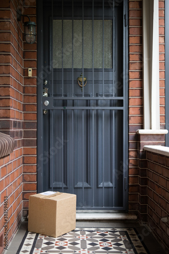 A parcel delivery of a brown cardboard box containing goods purchased online and delivered contactless to front doo