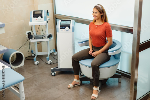 Obraz na plátne Happy woman during electromagnetic procedure for urinary incontinence at medical clinic
