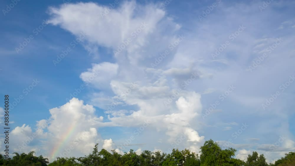 Time-lapse fluffy cumulus clouds and small half radius rainbow or spectrum in clear blue sky. Landscape and skycaps background. Time-lapse fluffy cumulus clouds and small half radius rainbow or spectrum in clear blue sky. Landscape and skycaps background.