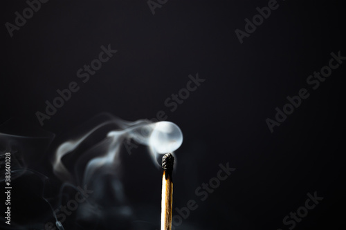Unlit wooden match giving off smoke with black background. Frontal Plane.