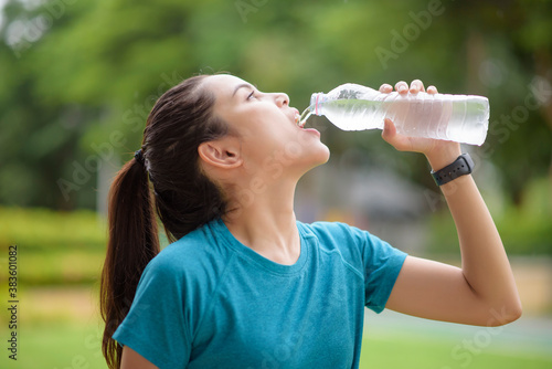 Fitness woman is drinking water after workout in park