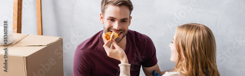 panoramic concept of woman feeding boyfriend with tasty pizza