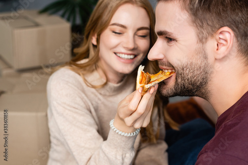 selective focus of woman feeding bearded man with pizza